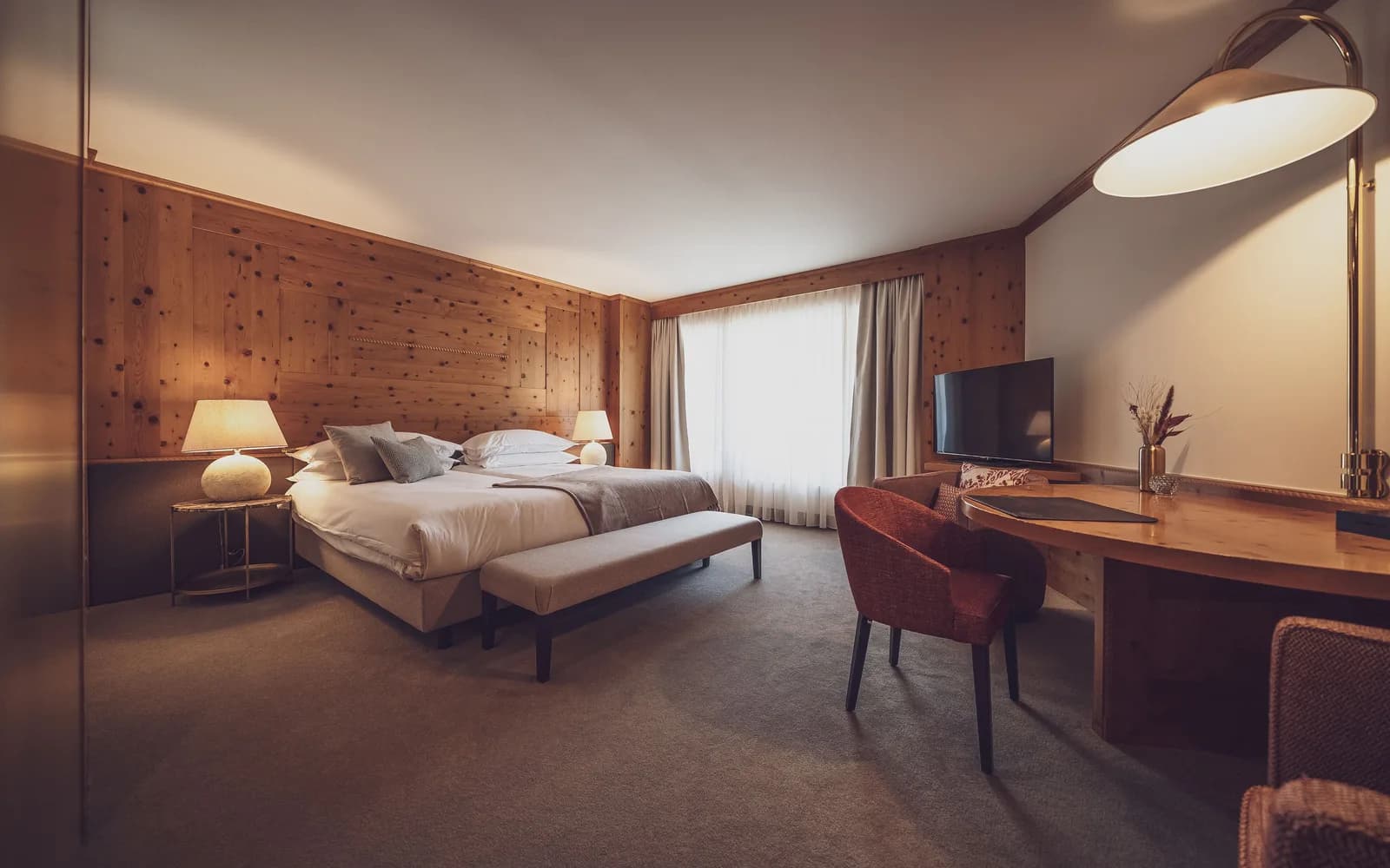 A luxury alpine hotel suite in Davos, with a wood-panelled bedroom in traditional Swiss chalet style.