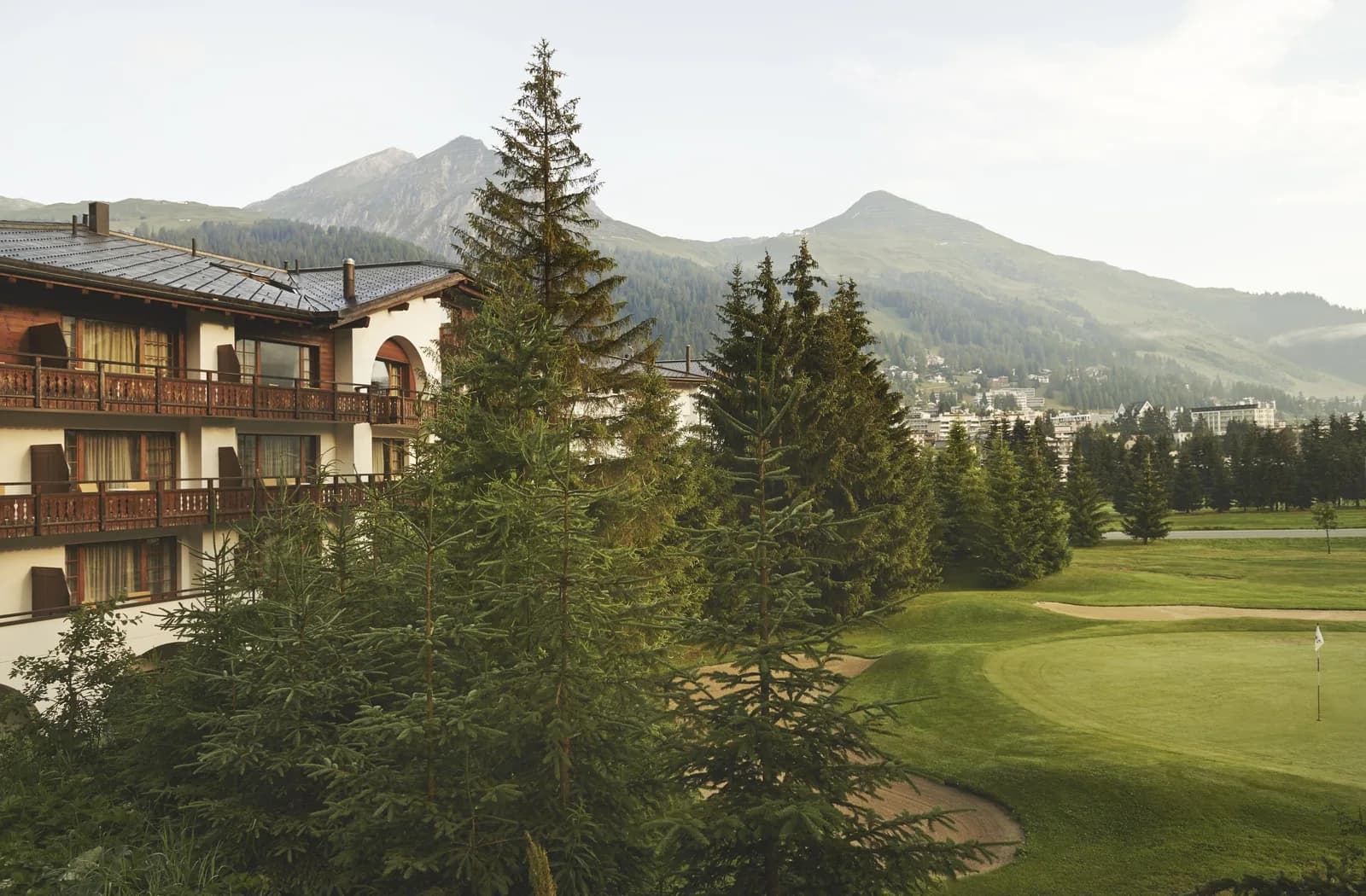 A traditional chalet-style Davos hotel beside the golf course, with the Grisons mountains behind.