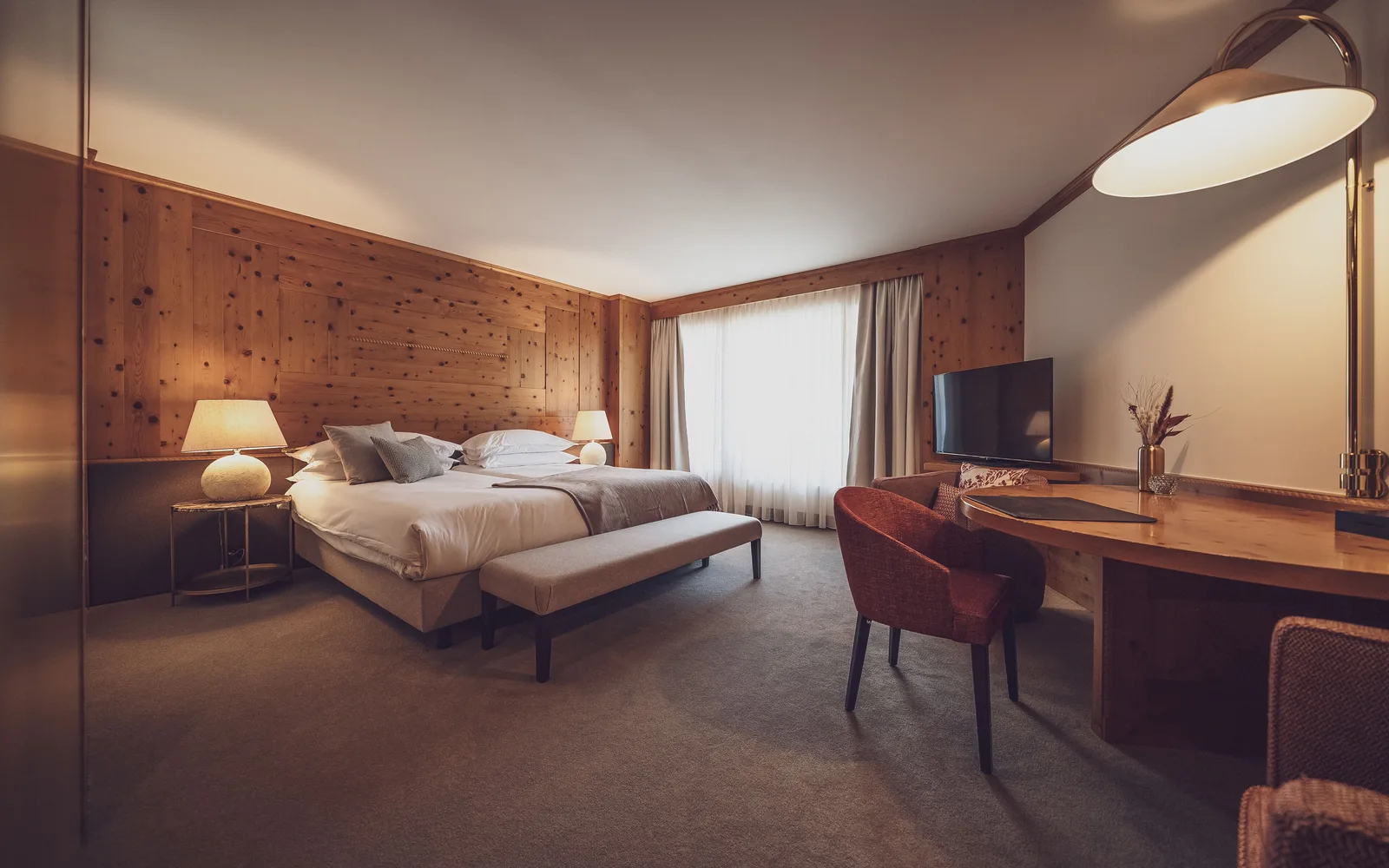 A luxury alpine hotel suite in Davos, with a wood-panelled bedroom in traditional Swiss chalet style.