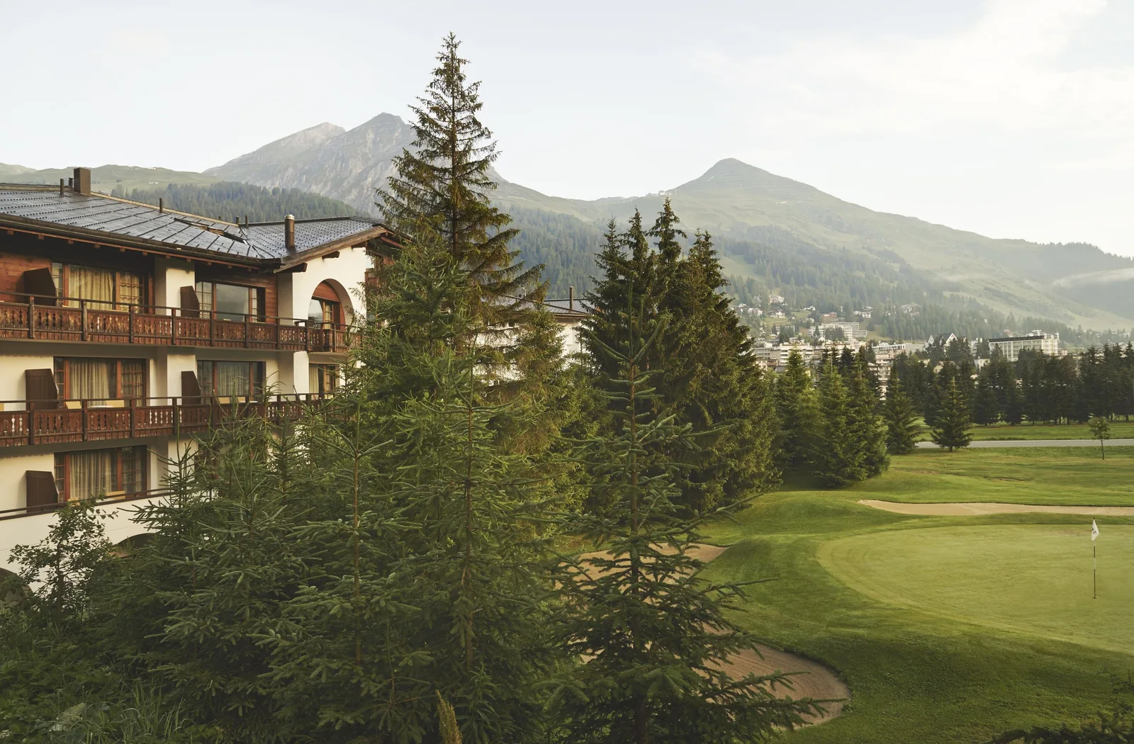 A traditional chalet-style Davos hotel beside the golf course, with the Grisons mountains behind.